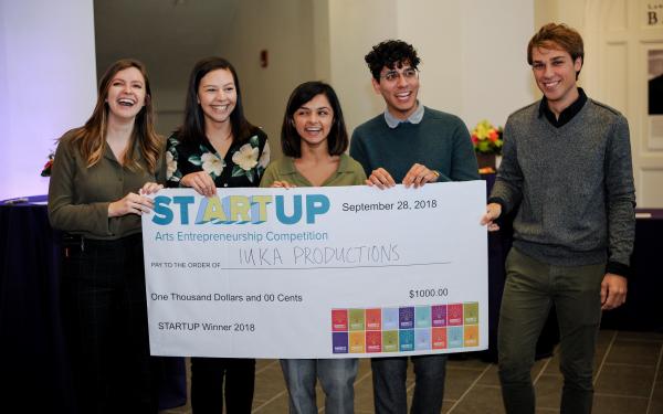 Iuka Productions student group, posing behind the $1,000 check they won at the StARTup competition at the 2018 Barnett Symposium. StARTup is Ohio State's first arts entrepreneurship competition.