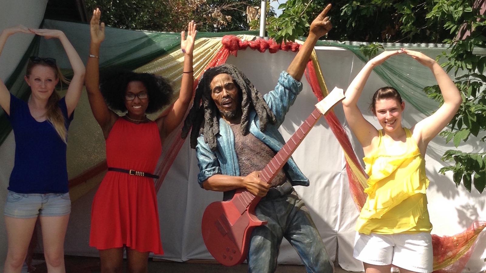 Students pose with a statue of Bob Marley in Kingston, Jamaica