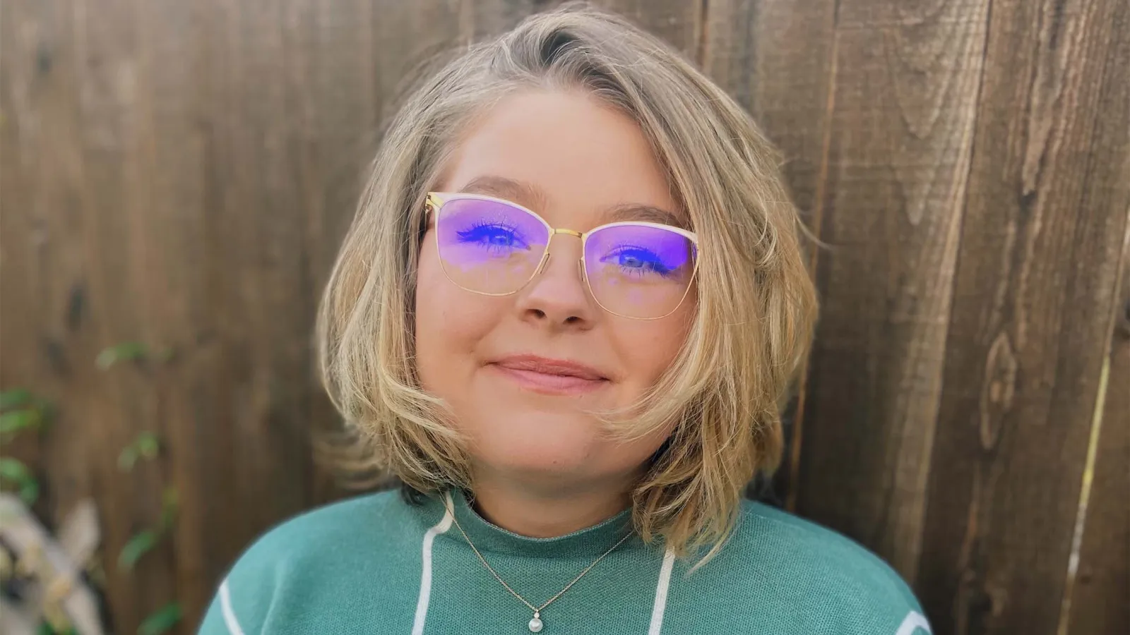Woman wearing glasses and aqua sweater with short, blonde hair