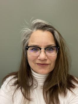 Woman in glasses wearing white turtleneck, looking at camera