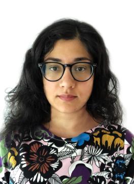 Woman with long, dark hair and glasses looking at camera