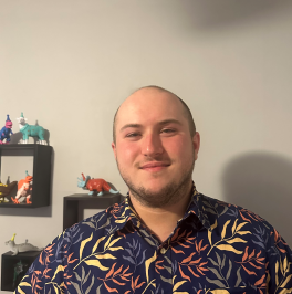 Zach Seltzer in front of beige wall smiles at camera