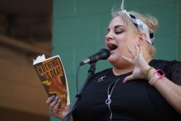 Slam poet reads from book while speaking into a microphone