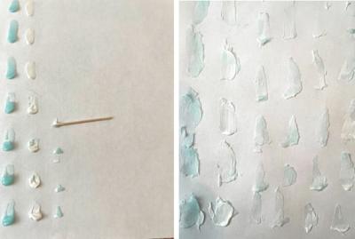 A series of toothpaste blobs line vertically along the left side of a piece of paper, a toothpick lays horizontally in the center of the paper. A series of aqua and white toothpaste blobs cover a piece of white paper.