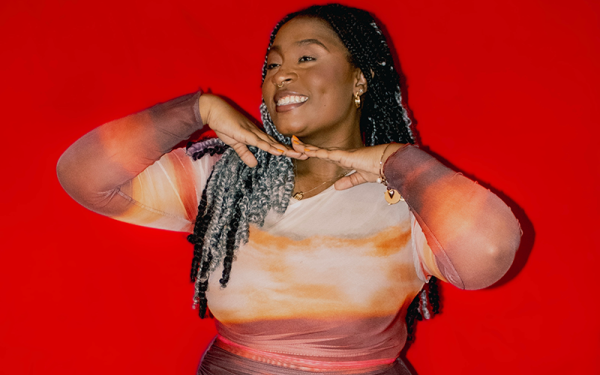 A woman smiles in front of a bright red background