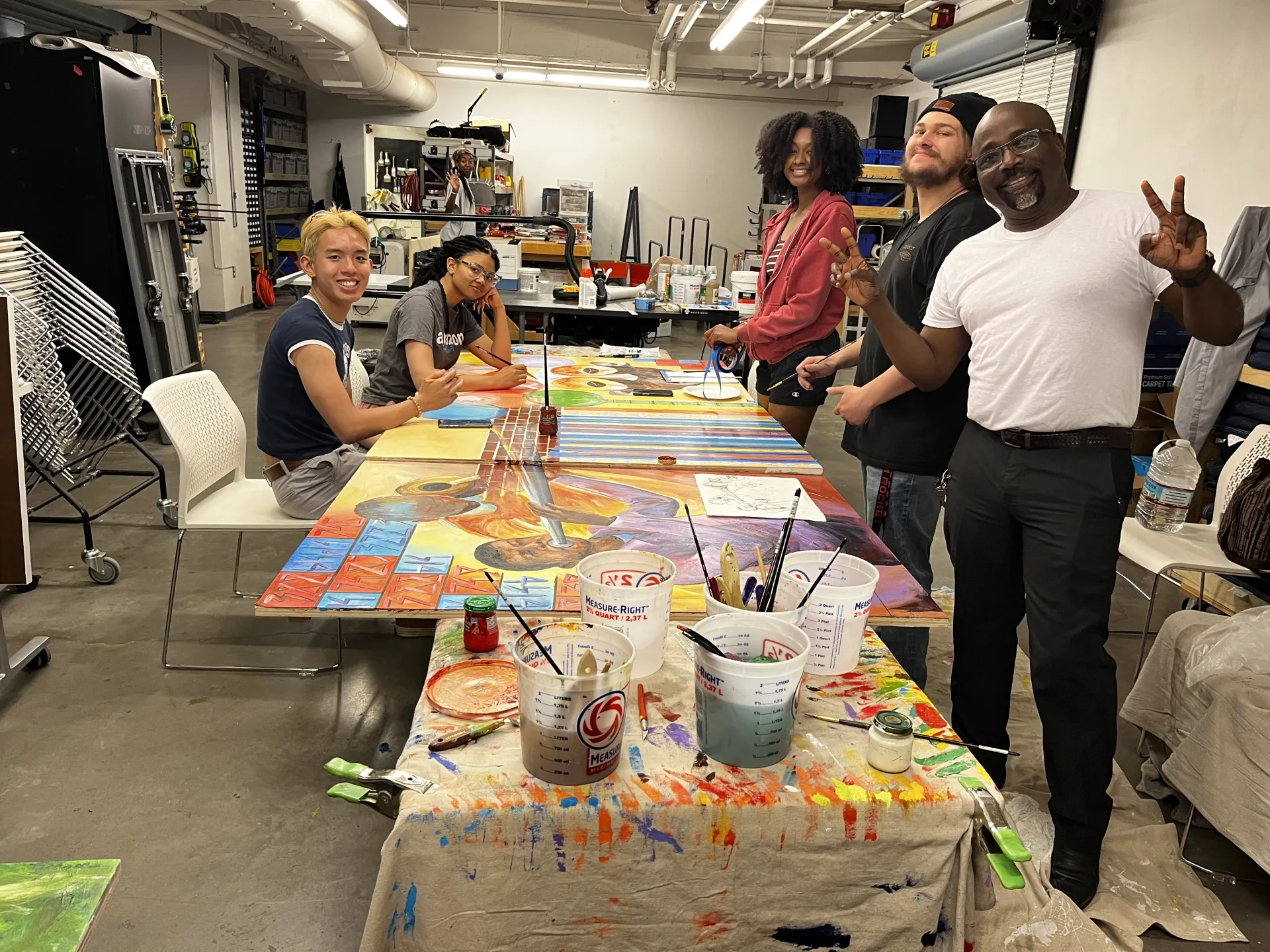 People stand around table painting colorful murals
