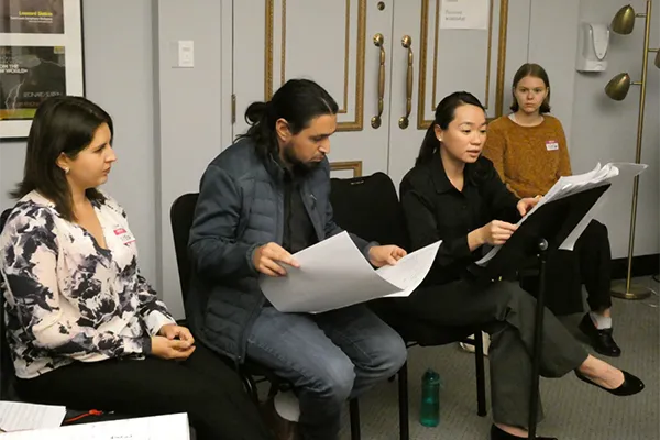 Four people look at sheet music