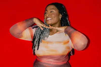 A woman smiles in front of a bright red background