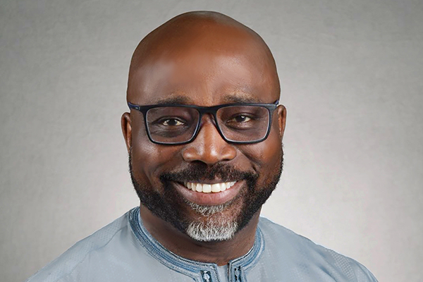 Man wearing glasses with goatee smiles at camera