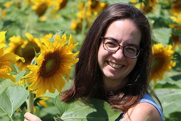 Ruth Smith in a field of sunflowers as she smiles at the camera