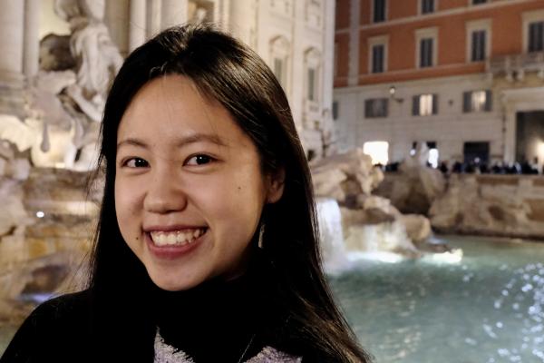 A woman smiling at the camera in front of a fountain