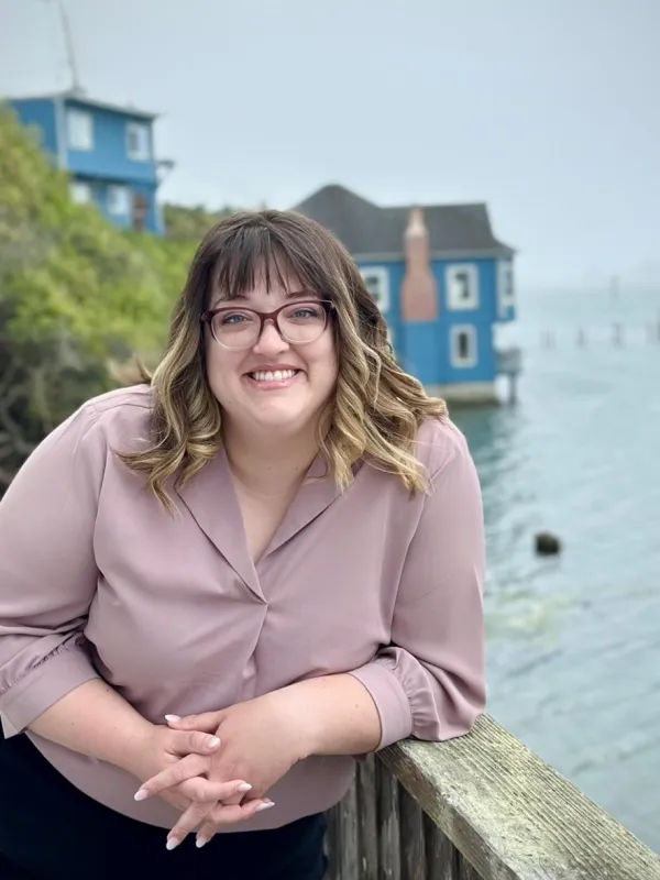 A person leaning on a railing by water