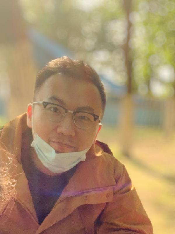 Yiran Zhao sitting in wooded area while wearing a jacket