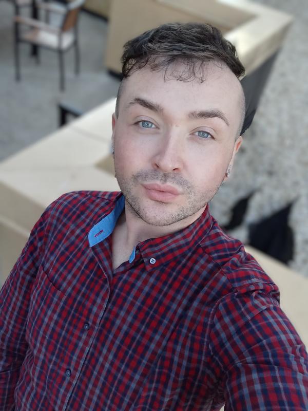 A person wearing a plaid shirt taking a selfie
