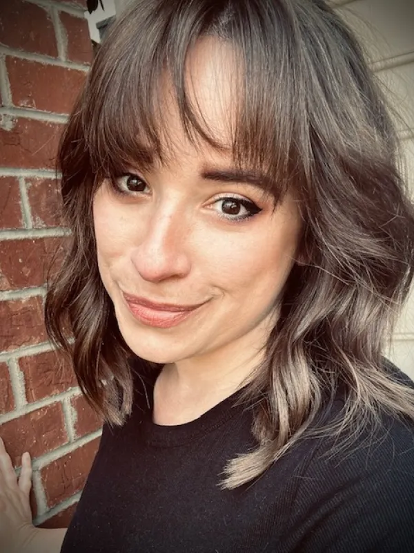 A person taking a selfie in front of a brick wall