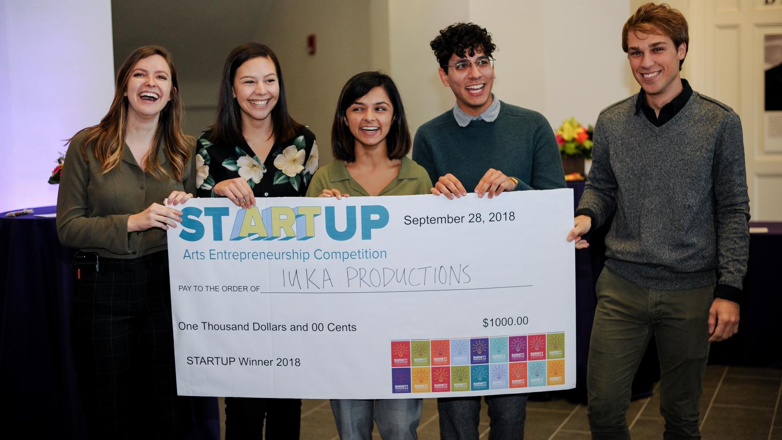 Iuka Productions student group, posing behind the $1,000 check they won at the StARTup competition at the 2018 Barnett Symposium. StARTup is Ohio State's first arts entrepreneurship competition.