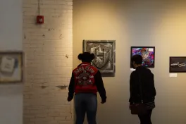 Two students with back to camera view art exhibit